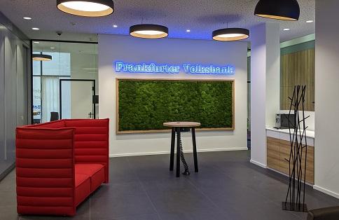 Münch+Münch Frankfurter Volksbank Filiale der Zukunft – Blick in den offenen Raum mit rotem Sofa und Mooswand